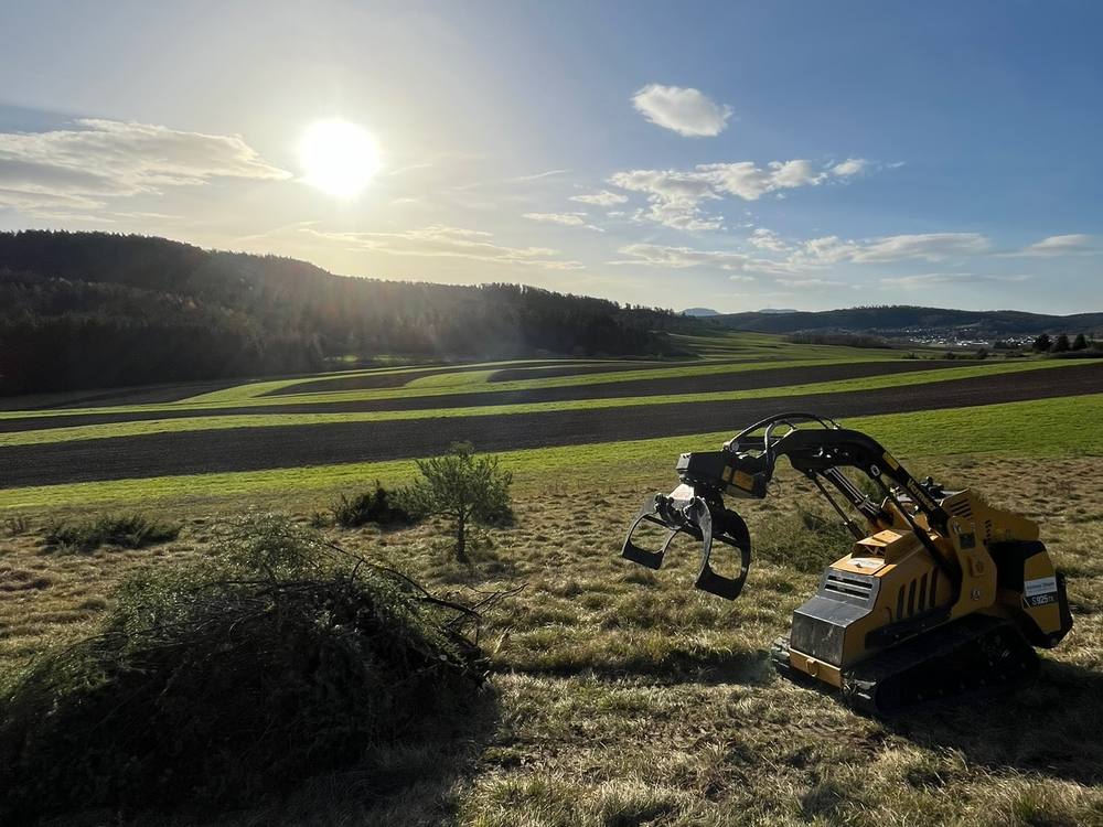 Kompaktlader von Steger auf einer Wiese im Abendlicht